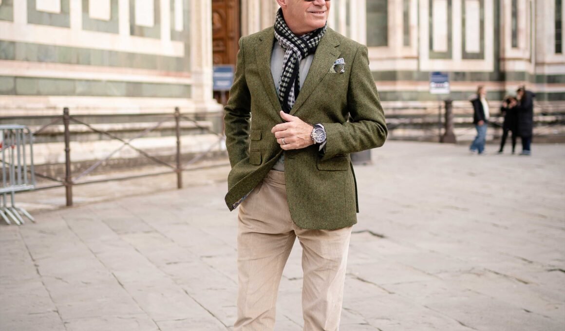 Richard marche dans les rues de Florence avec un veston vert et un pantalon beige, dans un style italien décontracté.